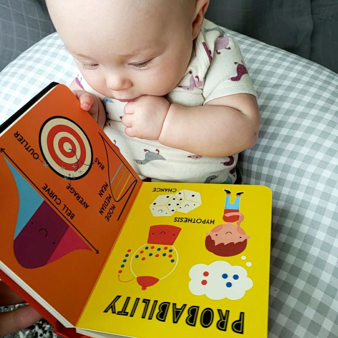 Baby holding a book about probability